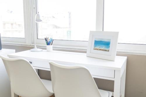a white desk with white chairs and a picture at The Skyward Flats in Nea Smyrni