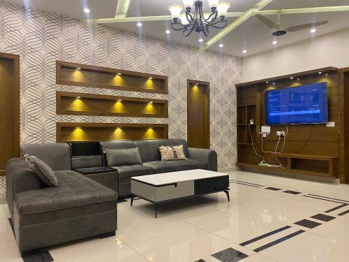 ein Wohnzimmer mit einem Sofa und einem TV in der Unterkunft Luxury Guest House in Bahria Town in Rawalpindi