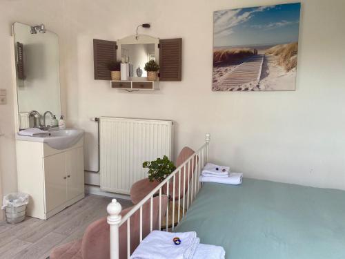 een badkamer met een wieg, een wastafel en een spiegel bij B&B de Zandtaart in Egmond aan Zee