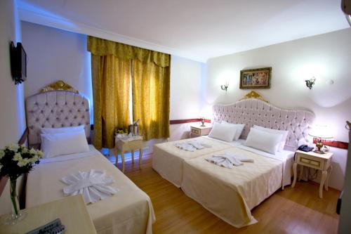 a hotel room with two beds and two tables at Adora Hotel in Istanbul