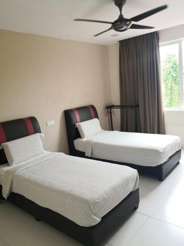 a room with two beds and a ceiling fan at KompoVilla House No 30 in Kuantan