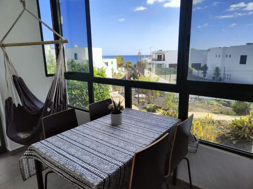 stół i krzesła w pokoju z dużym oknem w obiekcie Ailana Suite Vistas al Mar y con Piscina w Costa Teguise