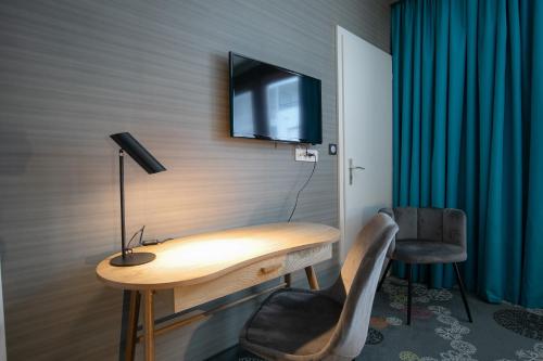 a room with a wooden desk with a television on the wall at Hôtel Restaurant Vaillant proche Europapark Rulantica in Sélestat
