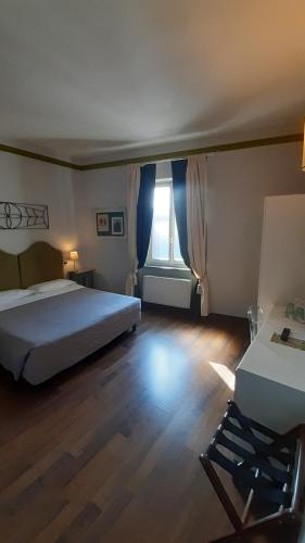 a bedroom with a bed and a chair and a window at Albergo Moderno in Lucca