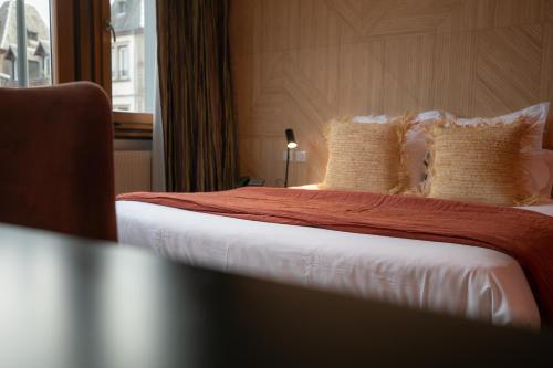 a hotel room with a bed with white sheets and pillows at Hôtel Restaurant Vaillant proche Europapark Rulantica in Sélestat