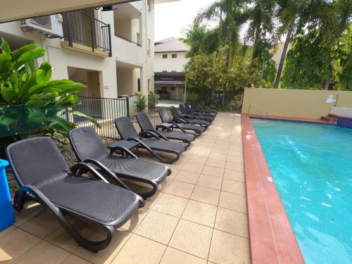 a row of lounge chairs next to a swimming pool at Central Plaza Port Douglas in Port Douglas