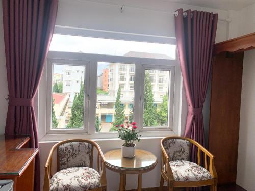 ein Fenster mit zwei Stühlen und einem Tisch mit Blumen darin in der Unterkunft Khách sạn Nam Ngọc Đà Lạt in Da Lat