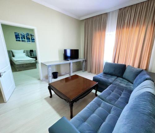 a living room with a blue couch and a table at Aktau Airport Hotel in Aktau