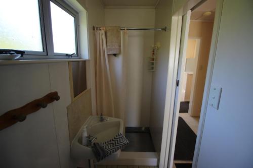 uma pequena casa de banho com um lavatório e uma janela em Cottage - Whanarua Bay Cottages em Te Kaha