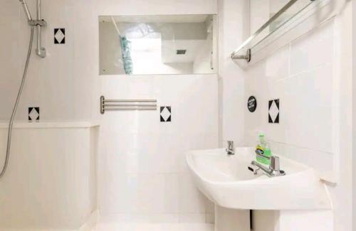 a white bathroom with a sink and a mirror at The Hideaway, Family apartment close to the beach. in Paignton