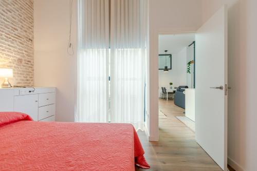 a white bedroom with a red bed and a hallway at HoneyMoon Apartment in Seville