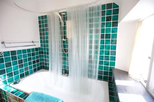 a bathroom with green tiles and a tub with a shower at Penkenna House, Crackington Haven, North Cornwall in Crackington Haven