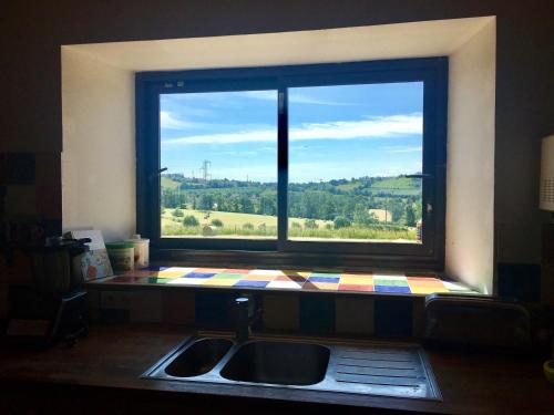 ein Fenster über einem Waschbecken in einer Küche mit Aussicht in der Unterkunft Maison spacieuse avec vue sur la montagne à Naucelles in Aurillac