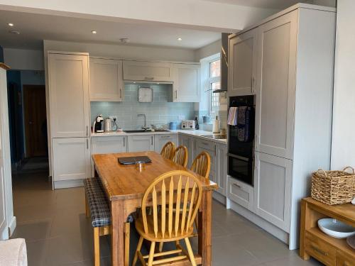 a kitchen with white cabinets and a wooden table at Charming 3 bed house and garden, pet friendly in Bournemouth