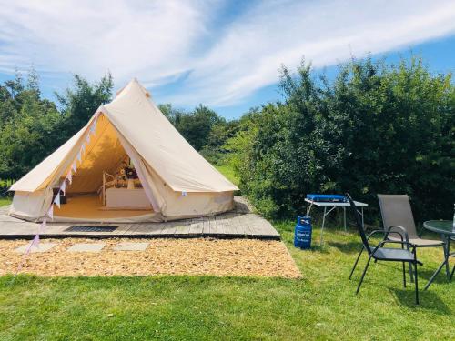 uma tenda num campo com uma mesa e cadeiras em Valley Farm Bells em Oxford