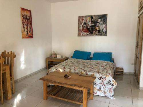 um quarto com uma cama com almofadas azuis e uma mesa em La Maison Aziz - Somone / Sénégal em Somone
