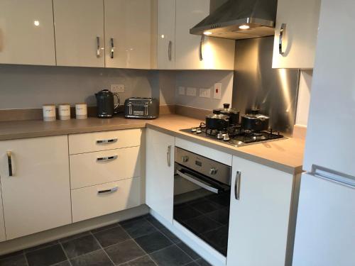 a kitchen with white cabinets and a stove top oven at Hill House - 5 Mins Merry Hill - Perfect for Contractors & Families in Brettell Lane