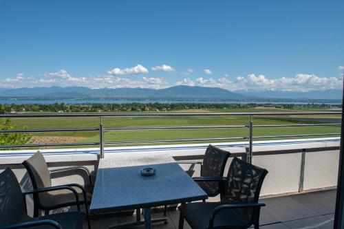 a table and chairs on a balcony with a view of a field at Everness Hotel & Resort in Chavannes-de-Bogis
