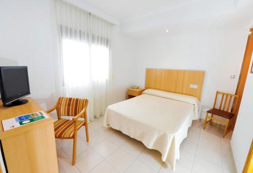 a bedroom with a bed and two chairs and a television at Hotel Montemar in Benidorm