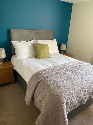 a bedroom with a large bed with a blue wall at Black Mountain Lodge in Glasbury