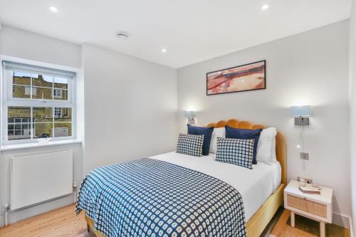 a bedroom with a bed with blue and white sheets at Cleveland Street by Q Apartments in London