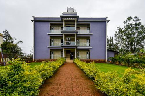 a purple house with a red brick path leading to it at Treebo Trend Prince Palace in Mahabaleshwar
