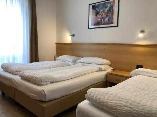 a group of three beds in a room at Hotel Derby in Folgarida