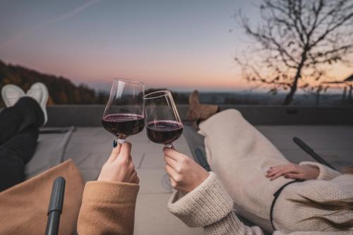 two people holding up glasses of red wine at Mountain Luxury Lodges in Slavetić