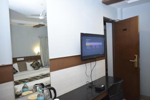 a television on a wall in a room with a bed at Hotel The Nook in Madurai