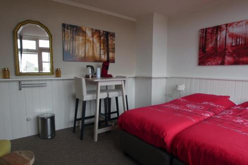 a bedroom with a red bed and a small table at Texelzon in Den Hoorn