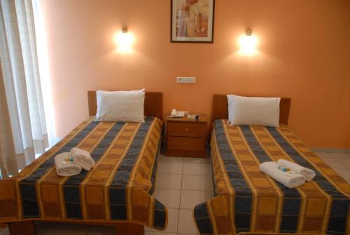 two beds in a hotel room with towels on them at Tzovanna Studios in Loutra Edipsou