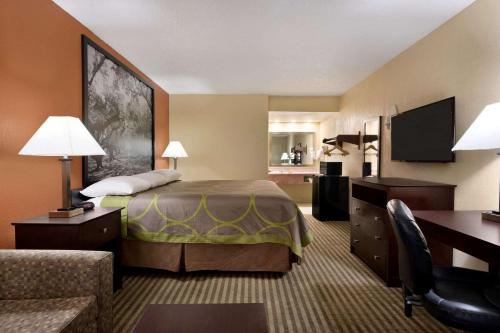 a hotel room with a bed and a desk at Super 8 by Wyndham Ruston in Ruston