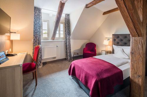 a hotel room with a bed and a desk and chairs at Best Western Hotel Schlossmühle Quedlinburg in Quedlinburg