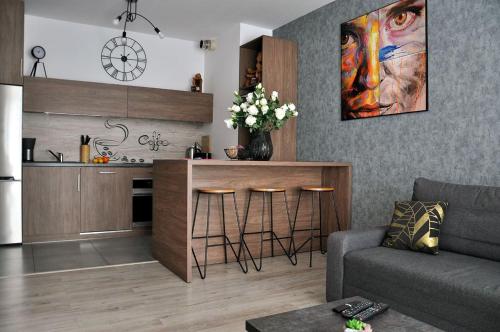sala de estar con cocina con encimera y taburetes en Q Apart Gold-3 Pokoje Manufaktura Garaż Netflix Klimatyzacja, FV, en Lodz