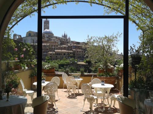 a patio with tables and chairs and a view of the city at Residenza d'Epoca Campo Regio Relais in Siena