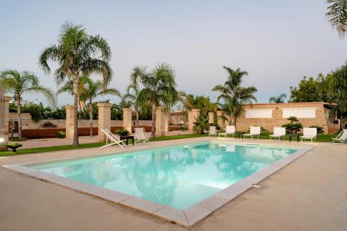 a large swimming pool with chairs and palm trees at Tenuta De Masi by LoveSud in Corsano