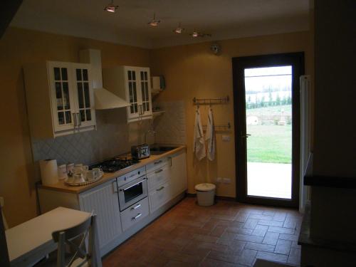 a kitchen with white cabinets and a door to a yard at Agriturismo Sant' Antonio di Saturnia in Manciano
