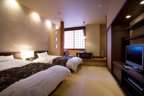 a hotel room with two beds and a flat screen tv at Yumetsuzuri in Omaki
