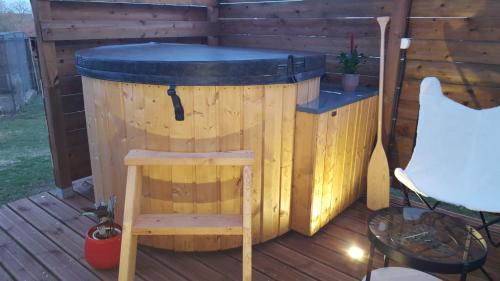 a hot tub on a deck with a table and a chair at LA ROULOTTE DES AMISH & Bain Nordique à Remous Jacuzzi in Mattexey