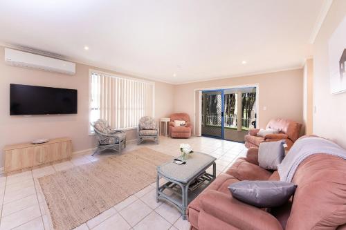 a living room with a couch and a flat screen tv at The Fairways 5 in Forster
