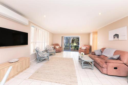a living room with a couch and a flat screen tv at The Fairways 5 in Forster