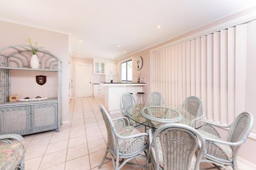a dining room with a glass table and chairs at The Fairways 5 in Forster