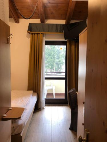a bedroom with a bed and a large window at Hotel Derby in Folgarida