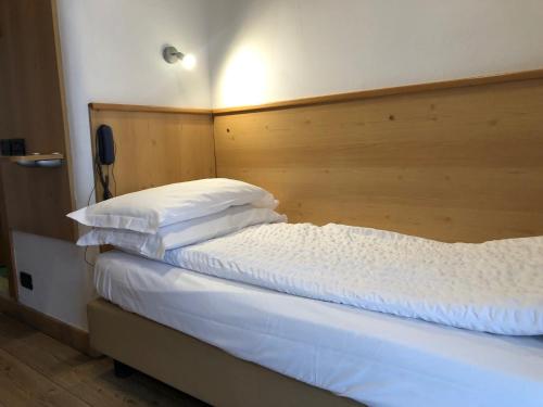 a bed with white sheets and pillows in a room at Hotel Derby in Folgarida