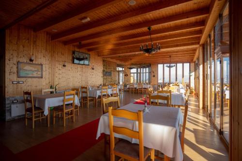 a dining room with tables and chairs and windows at Wooden House in Shkodër