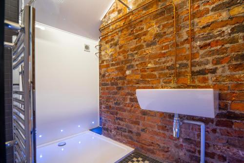 a bathroom with a brick wall and a white sink at Rooms by Green Room in Leeds