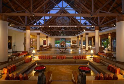 a lobby with a large hall with orange chairs at The Leela Kovalam, A Raviz Hotel in Kovalam