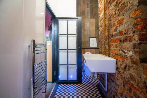 a bathroom with a sink and a brick wall at Rooms by Green Room in Leeds