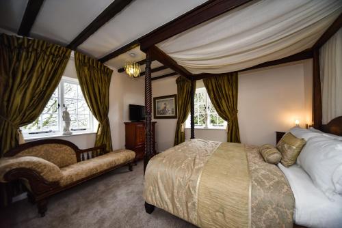 um quarto com uma cama de dossel e uma cadeira em The Bear Inn em Alderwasley