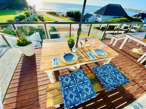 a wooden deck with a table and chairs and the ocean at My-konos in St Francis Bay